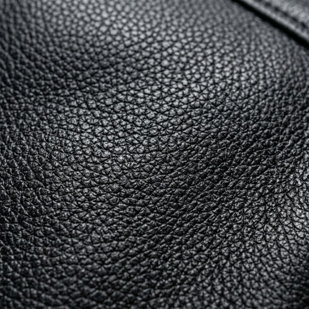 Close up photograph of goatskin leather surface texture showing the tight natural grain pattern that distinguishes it from cowhide