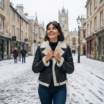 Woman wearing black shearling leather moto jacket with ivory fur collar in snow — Snowgrace by Snag Leather